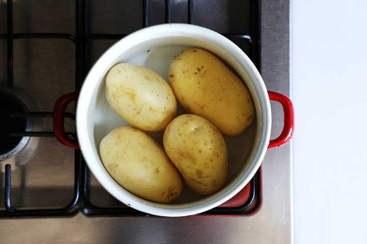Boiling waxy potatoes in red pot.