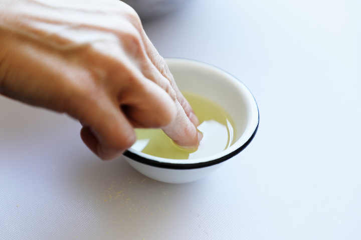 Dipping fingers in cooking oil in small bowl.