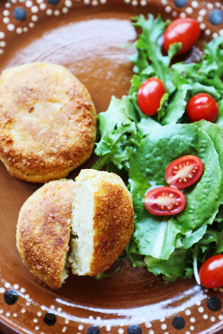 Mashed potato patties and a green salad with tomatoes.