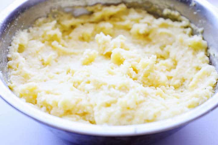 Potato, egg, and cheese mixture in stainless mixing bowl.