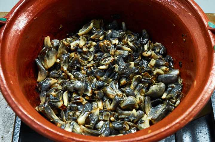 Cooked huitlacoche in clay pot on stove.