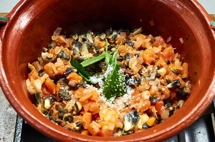 Huitlacoche quesadilla filling in clay pot on stove.