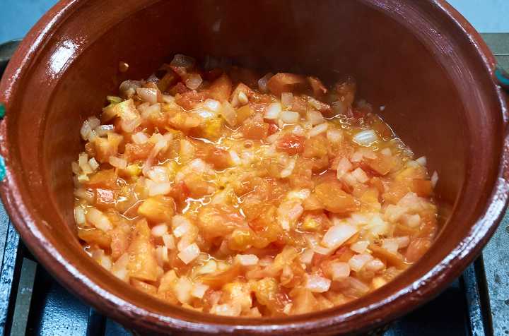 Simmering Onion, Tomato, Garlic in Pot on Stove.