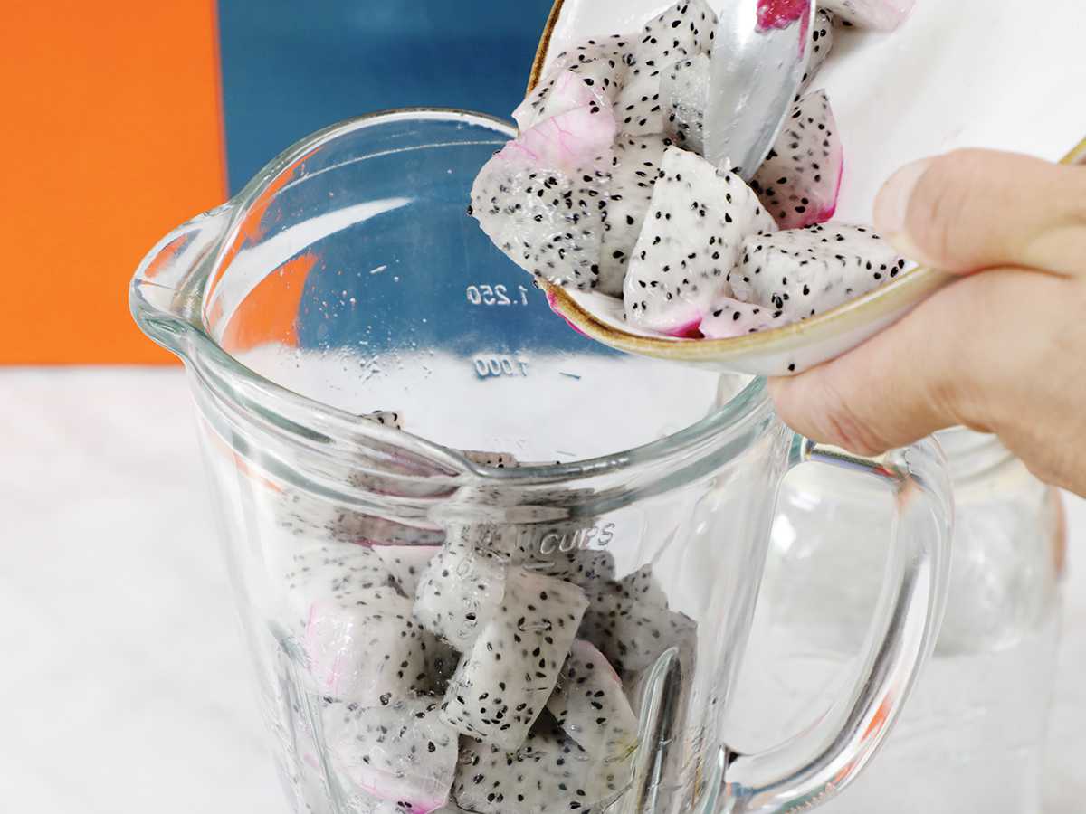 Adding chunks of dragon fruit to blender jar.