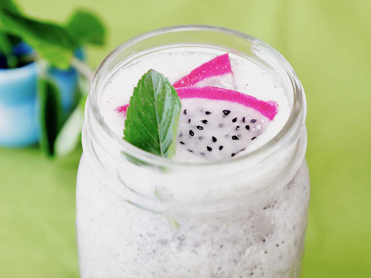 Close up of dragon fruit drink with fruit and mint leaf garnish.