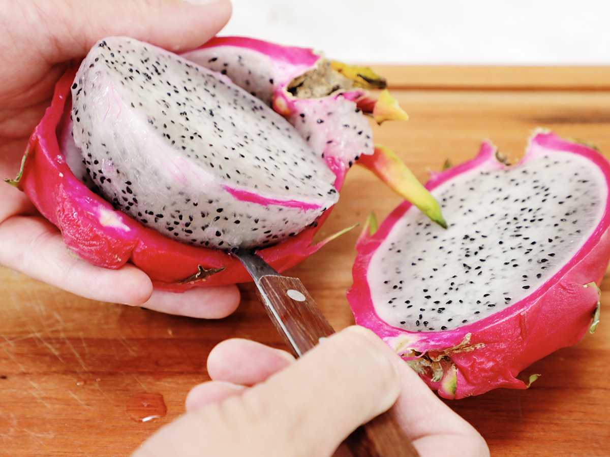 Scooping dragon fruit flesh with spoon.